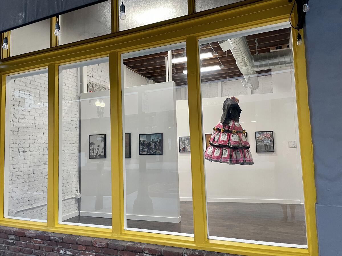 A window view of Crear Studio featuring La Maestra exhibition in downtown Santa Ana.