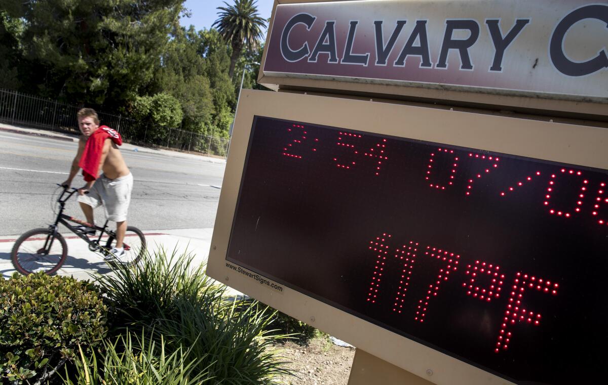 A bicyclist last year rides past a message board at Calvary Church in West Hills reads 117 degrees on July 6.