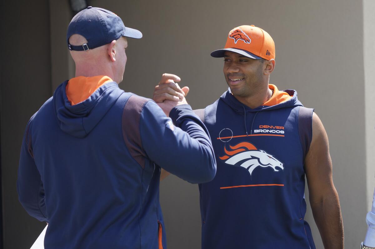 Denver Broncos head coach Nathaniel Hackett, left, greets quarterback Russell Wilson as he heads to a news conference before the NFL football team's practice Thursday, Sept. 8, 2022, at the Broncos' headquarters in Centennial, Colo. The Broncos open the NFL season Monday night against the Seahawks in Seattle. (AP Photo/David Zalubowski)
