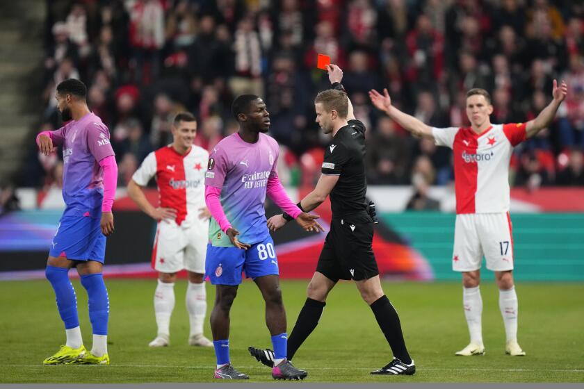 FILE - Referee Jindrich Trpisovsky shows the red card to the Slavia's Tomas Holes, second left at rear, during the Europa League group of 16 second leg soccer match between Slavia Praha and AC Milan at the Fortuna Arena in Prague, Czech Republic, Thursday, March 14, 2024. Slavia Prague has been fined by UEFA a total of 87,000 euros ($93,000) for crowd trouble during the Europa League game against AC Milan. Also, Slavia captain Tomas Holes who received a red card in the 20th minute is banned for one game in European competitions. (AP Photo/Petr David Josek, File)