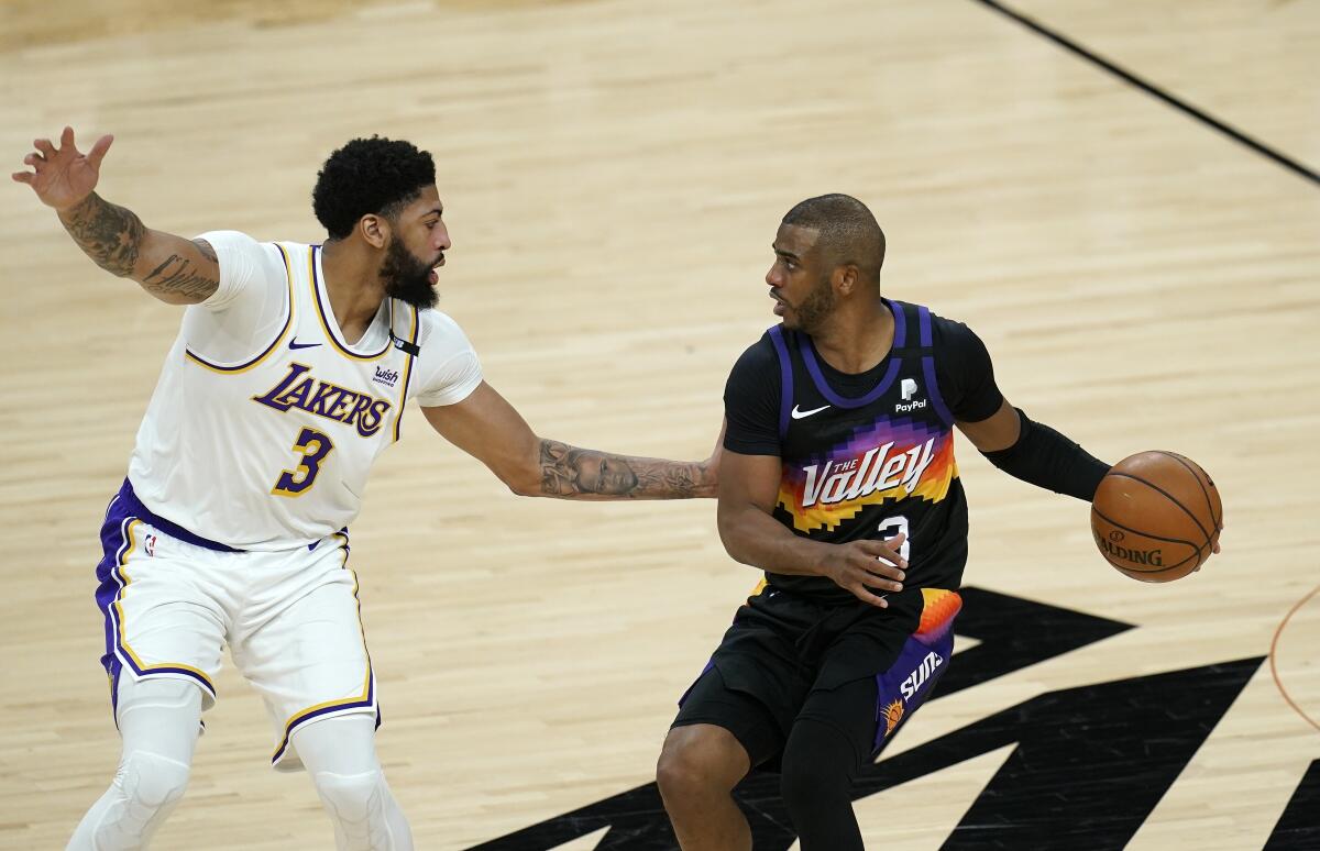 Phoenix Suns guard Chris Paul, right, controls the ball in front of Lakers forward Anthony Davis.