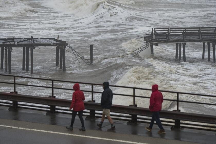 People walk along Cliff Drive to view the Capitola Wharf damaged by heavy storm waves in Capitola, Calif., Thursday, Jan. 5, 2023. (AP Photo/Nic Coury)