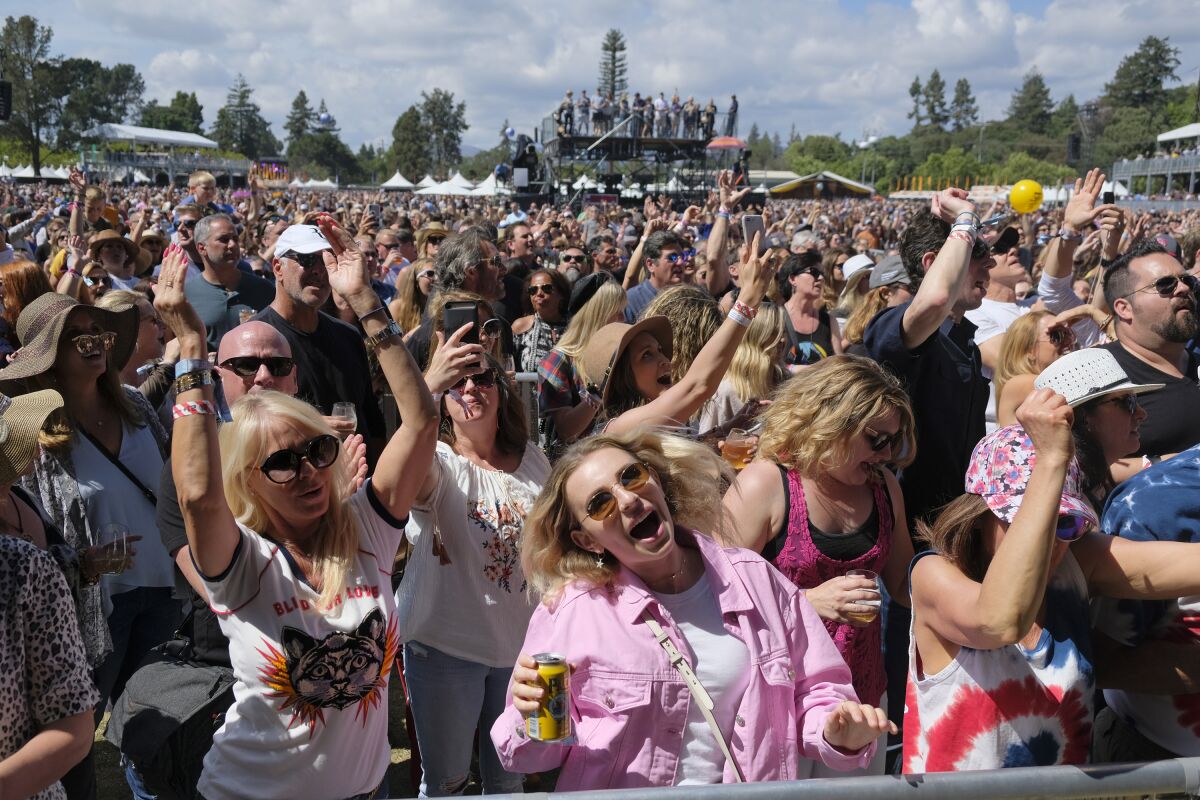 FILE - In this May 26, 2018, file photo, people listen to Michael Franti perform at the BottleRock Napa Valley music festival in Napa, Calif. Summer music festivals can be a once-in-a-lifetime experience, but costs can be excessive for many fans. With expenses for food, drinks, outfits, flights and hotels on top of the ticket price, budgeting for a festival can outperform even the best lineups. Taking advantage of credit card rewards for entertainment purchases, planning ahead for hidden costs, using a zero-interest payment plan or even partnering with festival brands through social media may make these special events more affordable. If your dream festival experience is still out of reach, don’t worry — there will always be another one.(AP Photo/Eric Risberg, File)