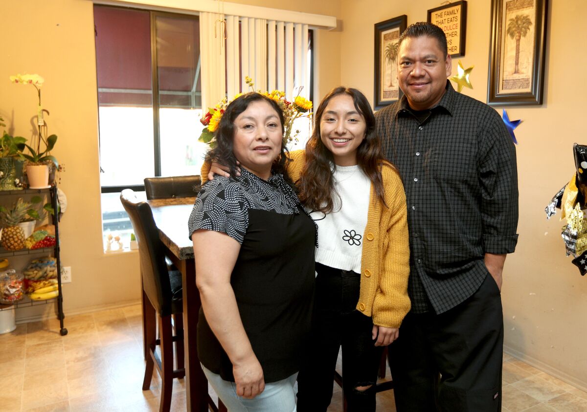Paola Mendoza, at home with her parents Claver Rosas, left and Cesar Mendoza, right.