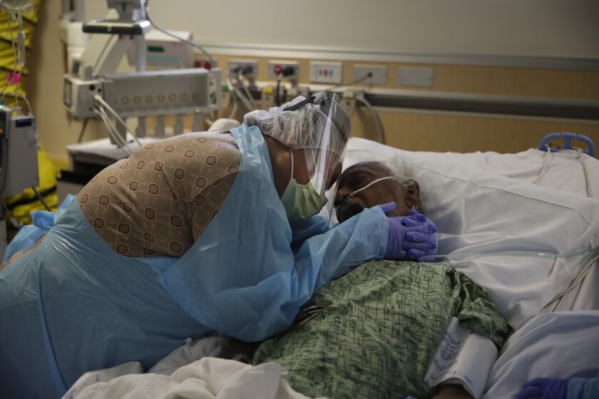 FILE - In this July 31, 2020, file photo, Romelia Navarro, 64, weeps while hugging her husband, Antonio, in his final moments in a COVID-19 unit at St. Jude Medical Center in Fullerton, Calif. The U.S. death toll from the coronavirus topped 300,000 Monday, Dec. 14, just as the country began dispensing COVID-19 shots in a monumental campaign to conquer the outbreak. (AP Photo/Jae C. Hong, File)