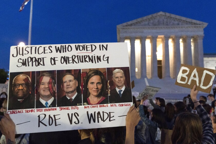 Demonstrators outside the Supreme Court hold pictures of justices who may be willing to overturn Roe vs. Wade.