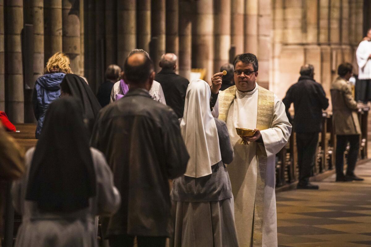 A priest distributes Communion at the Freiburg Cathedral in Freiburg, Germany, in 2020.