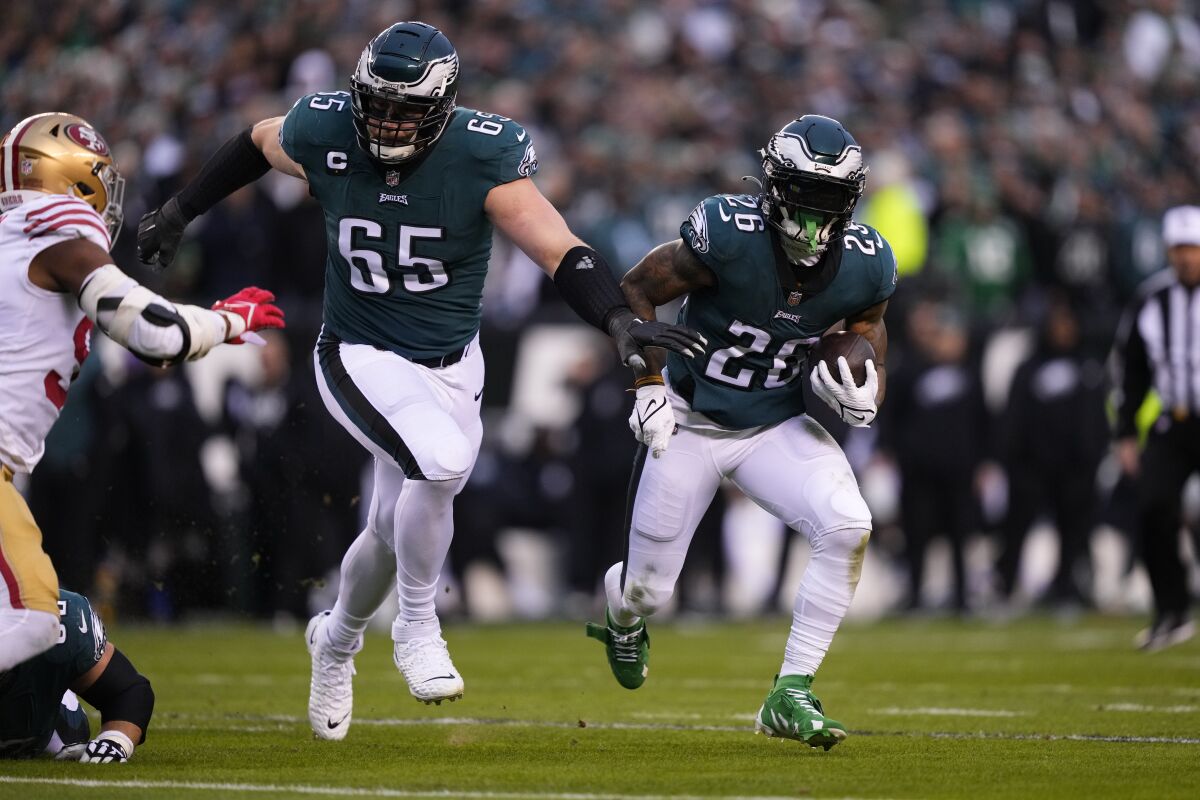 Eagles offensive tackle Lane Johnson (65) leads running back Miles Sanders (26) against the 49ers.