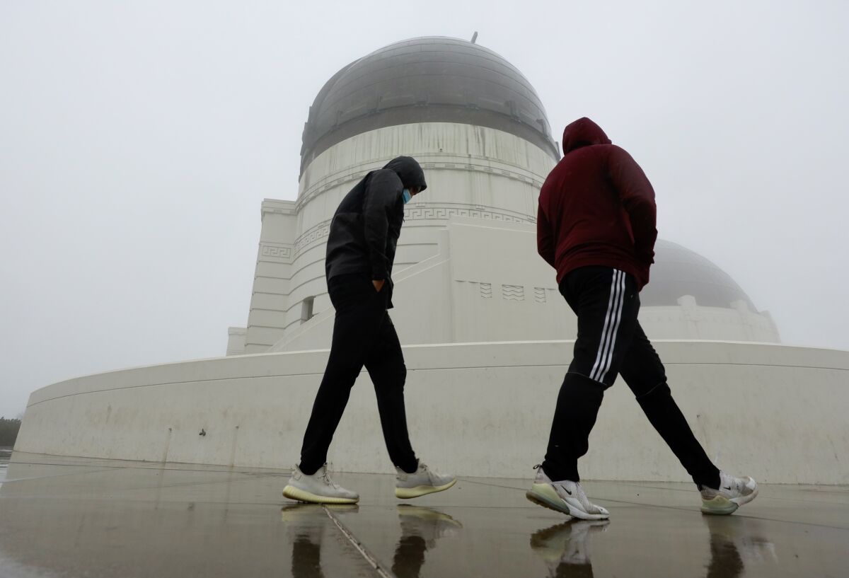 Tessie Edwards, left, and Eddie Medina brave the rain to visit Griffith Observatory in Griffith Park.