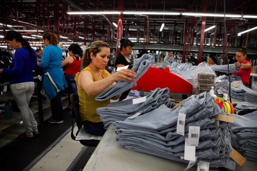 A factory worker uses an Avery fastener machine to attach price tickets and tags to garments.