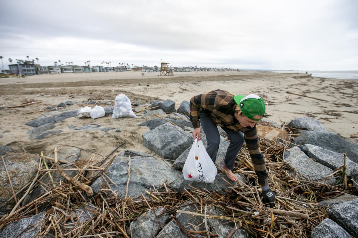 Spencer Clark picks up small pieces of trash along the jetty at the mouth of the Santa Ana River.