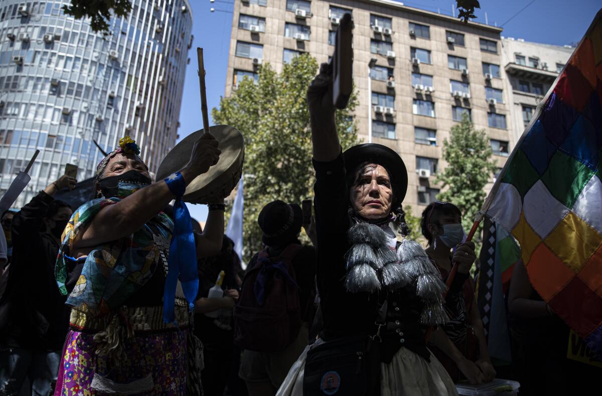 Mujeres indígenas mapuche y aymara sostienen instrumentos musicales 