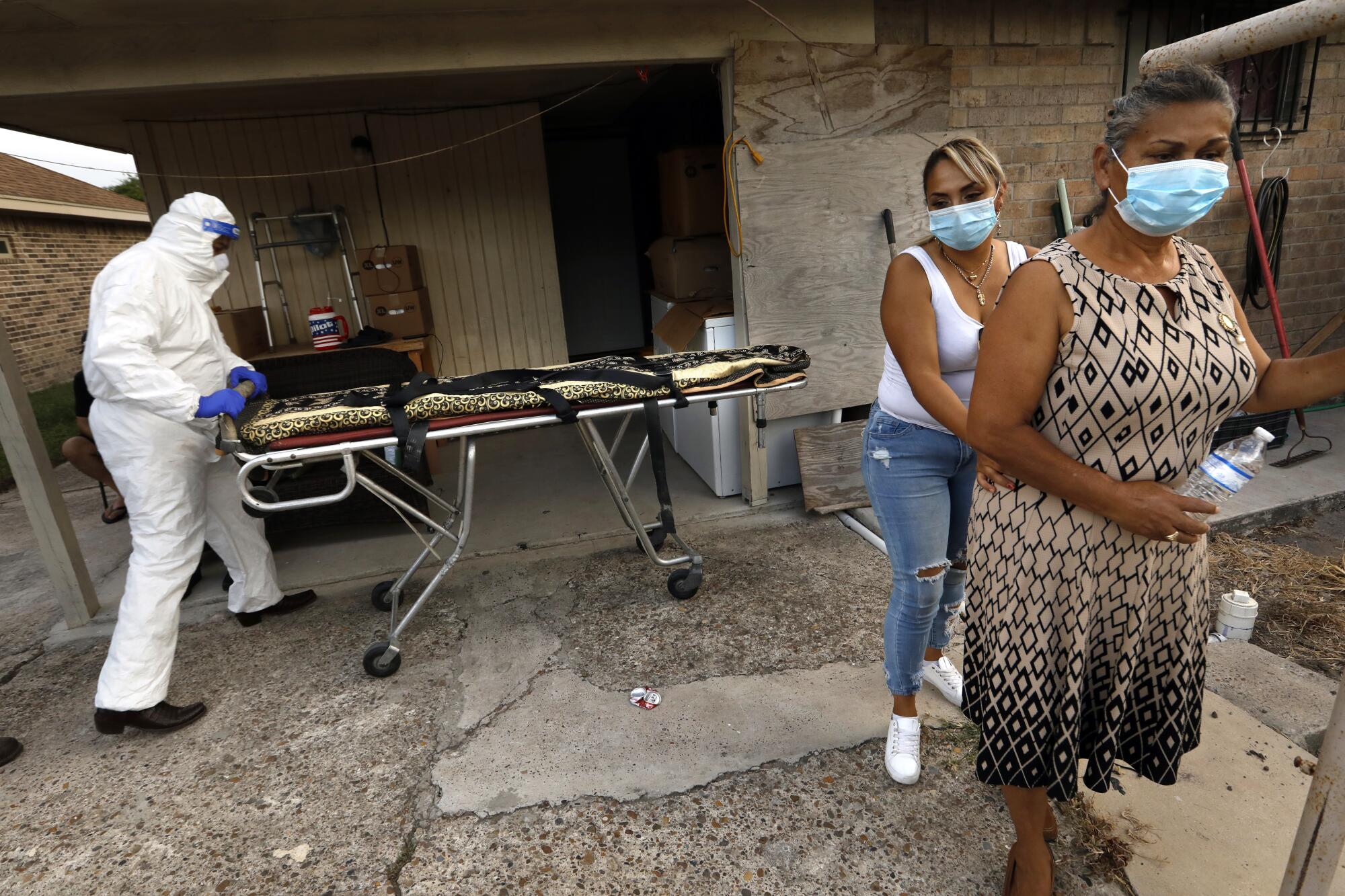 Juan Lopez wheels a gurney up to the home of Amalia Tinoco, 91, who died after becoming infected with COVID.