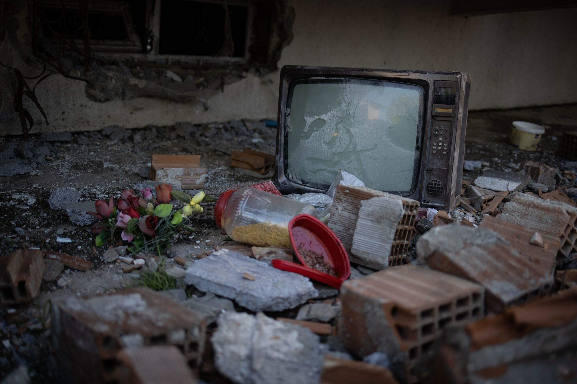 A TV and flowers are seen amid rubble in front of destroyed buildings in Antakya, Turkey.