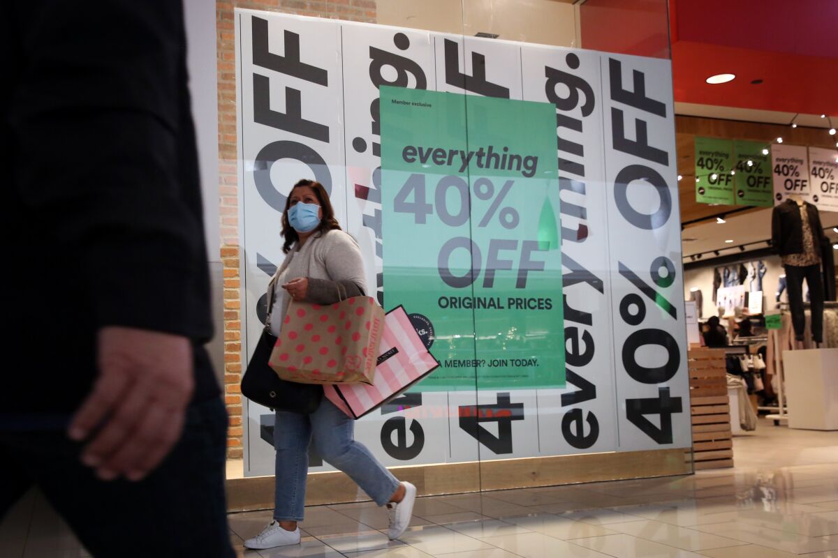 A woman walks in front of a mall store window advertising 40% off everything