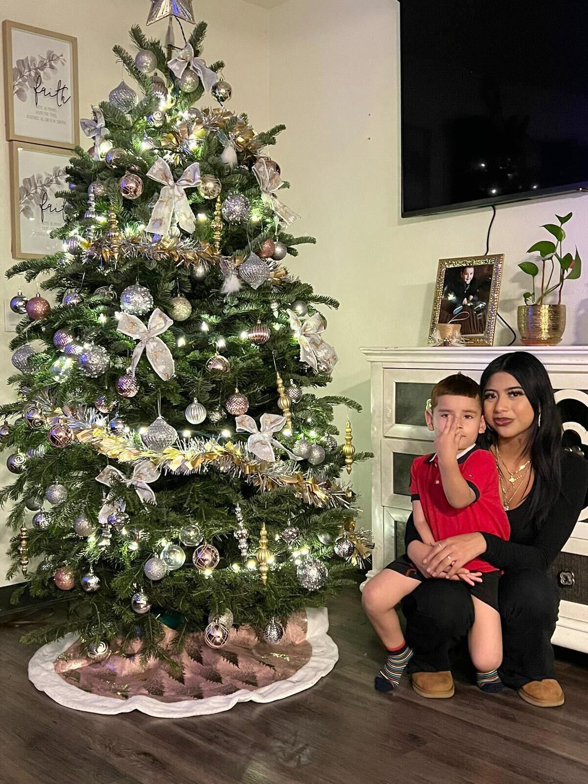 A teenager and her little brother next to a Chrismas tree.