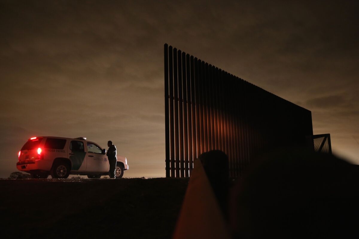 U.S. Border Patrol agents confer near a section of the U.S.-Mexico border fence near La Joya, Texas.