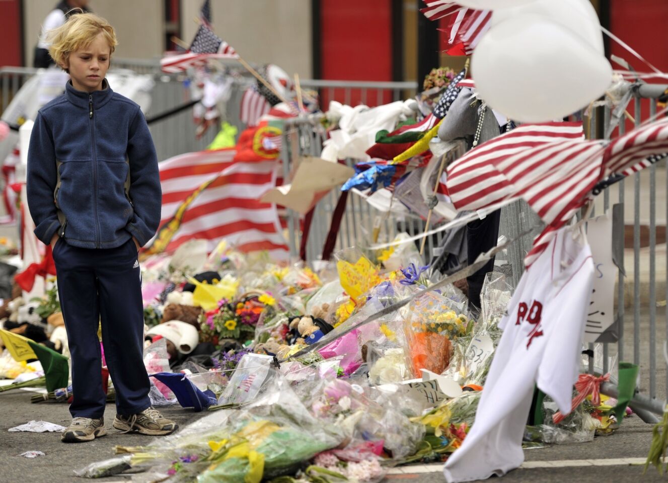 A boy contemplates a street memorial on Boylston Street, the scene of two explosions that killed three people Monday near the Boston Marathon finish line, as Bostonians began returning to normal life on the morning after the capture of the second of two suspects wanted in the bombings.