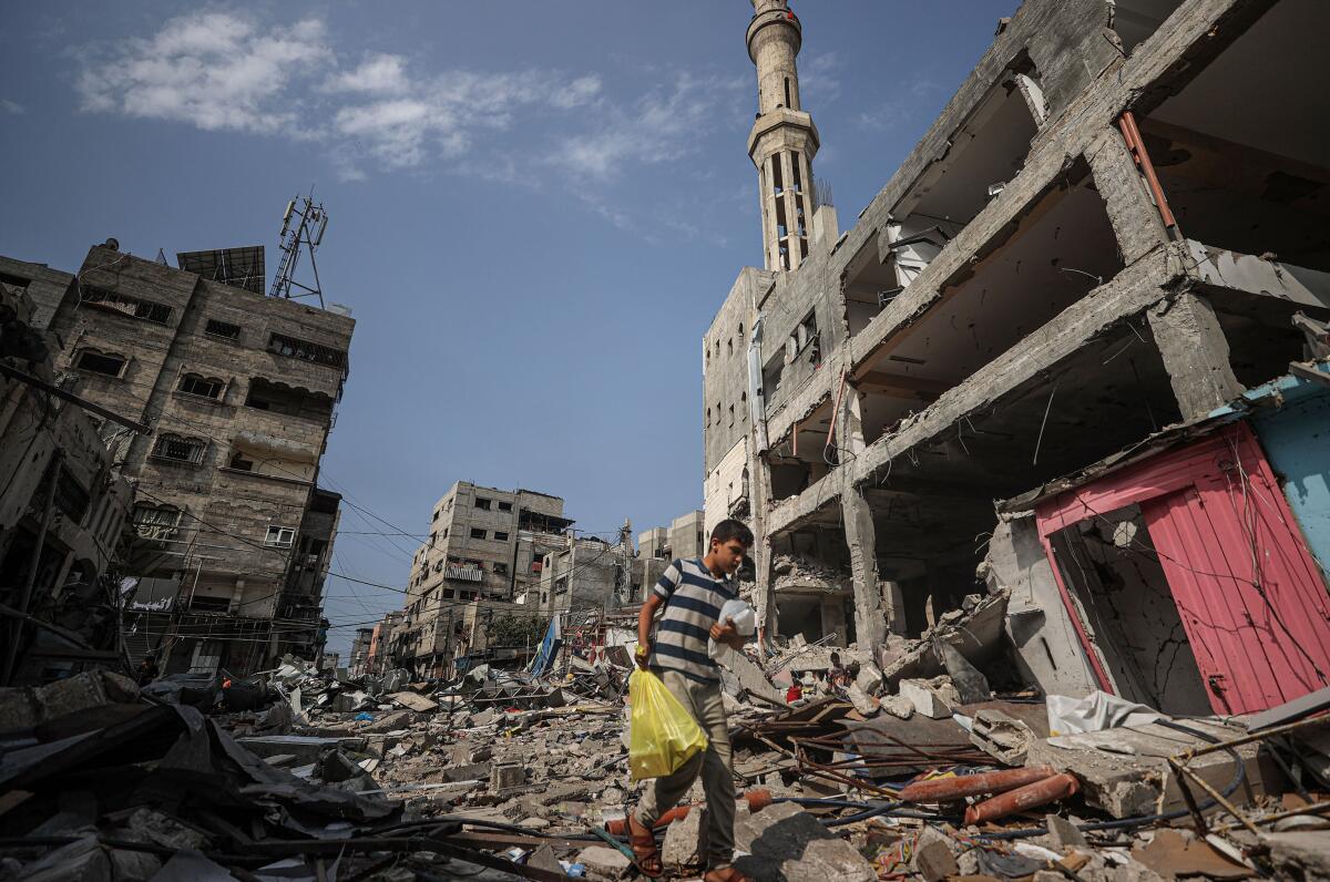 A boy walks among the rubble of collapsed buildings after Israeli attacks.