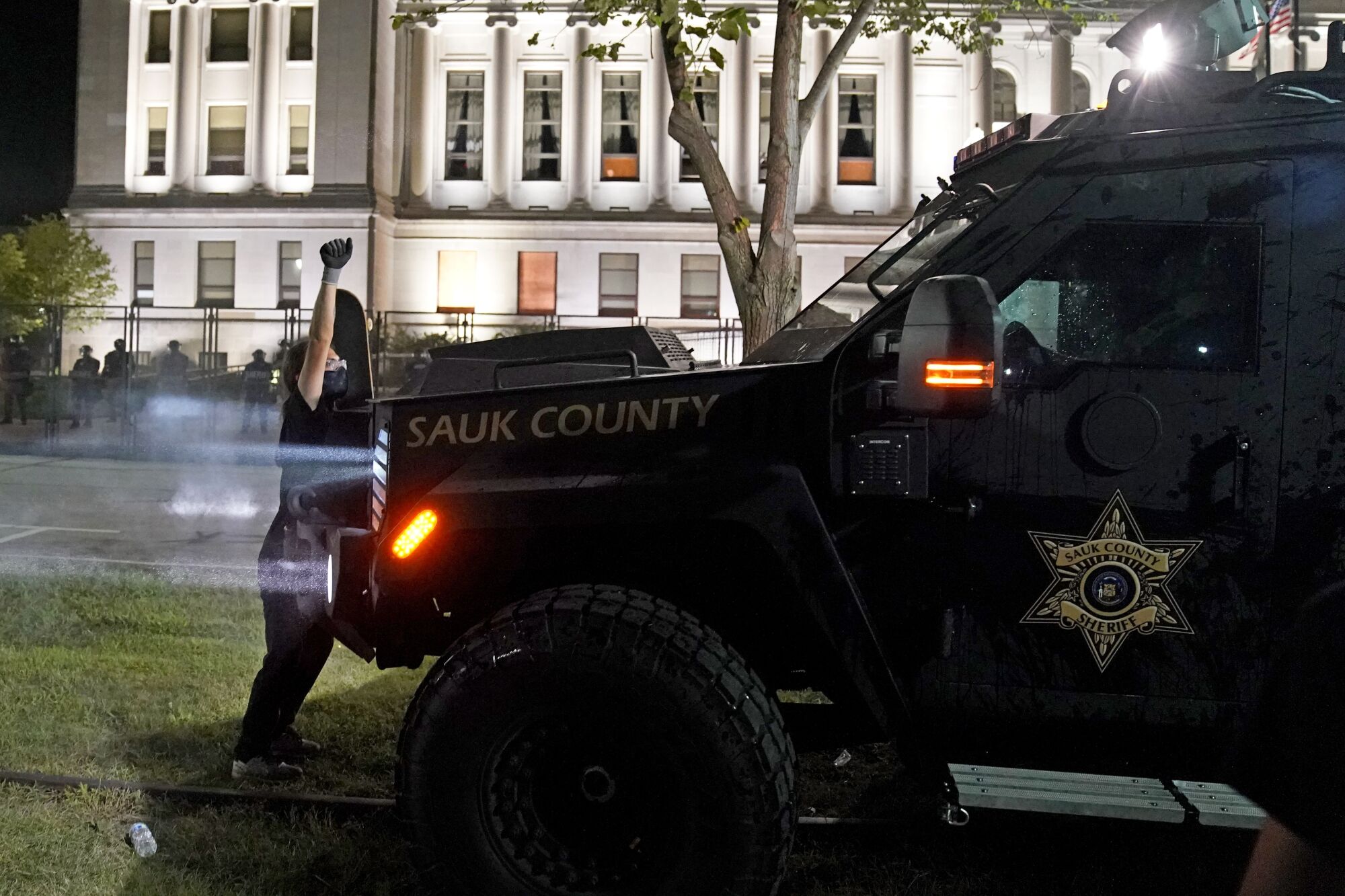 A protester stands in front of an armored vehicle trying to clear a park of demonstrators.