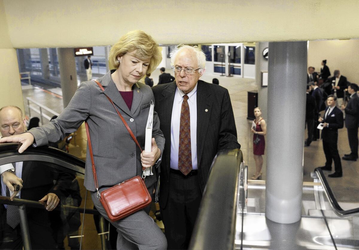 Senate Veterans Affairs Committee Chairman Bernie Sanders (I-Vt.) speaks with Sen. Tammy Baldwin (D-Wis.) as they take an escalator to the Senate chamber on Capitol Hill.