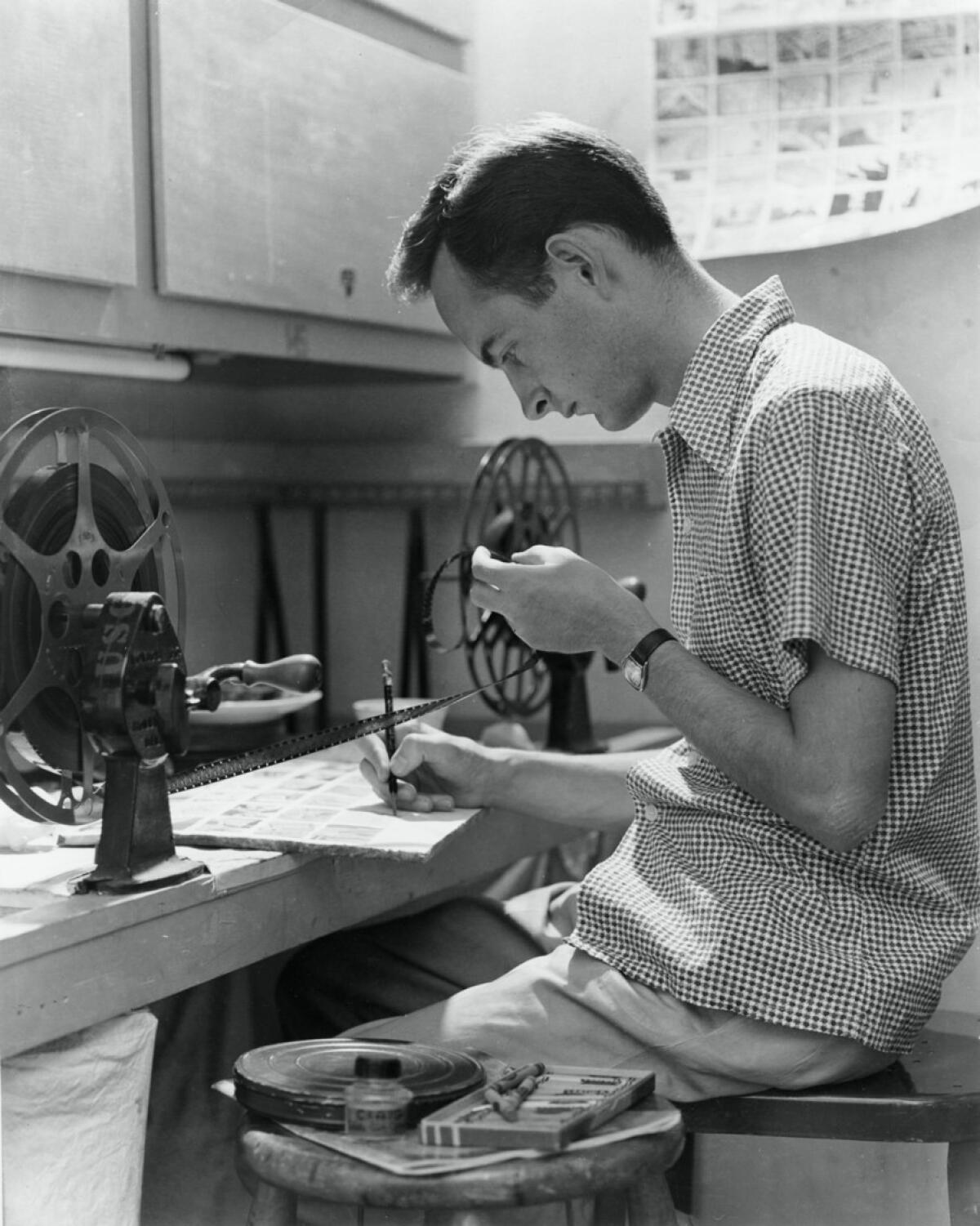 A vintage photo of a young man working with film editing equipment