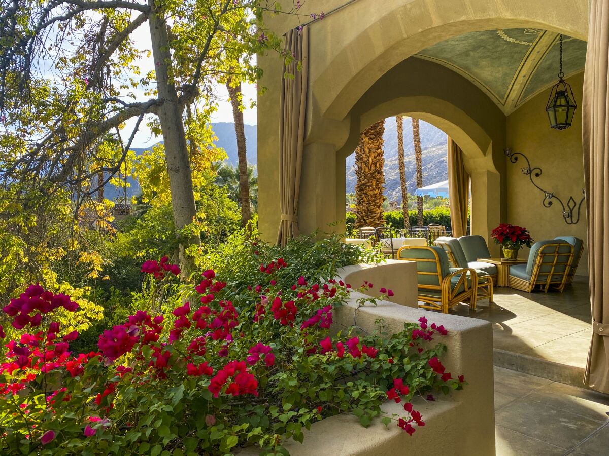 Patio of a hotel surrounded by flowers and greenery