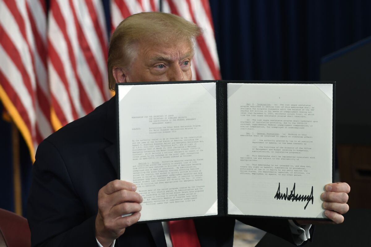 President Trump holds up a signed executive order during a news conference in Bedminster, N.J., on Aug. 8.