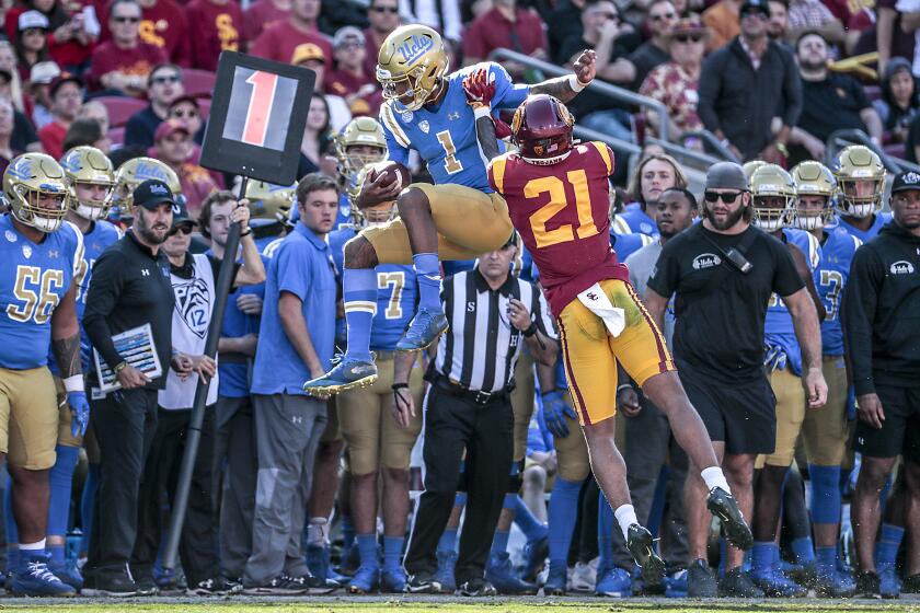 LOS ANGELES, CA, SATURDAY, NOVEMBER 23, 2019 - UCLA Bruins quarterback Dorian Thompson-Robinson is shoved out of bounds by USC Trojans cornerback Olaijah Griffin (2) during first half action at the Coliseum. (Robert Gauthier/Los Angeles Times)