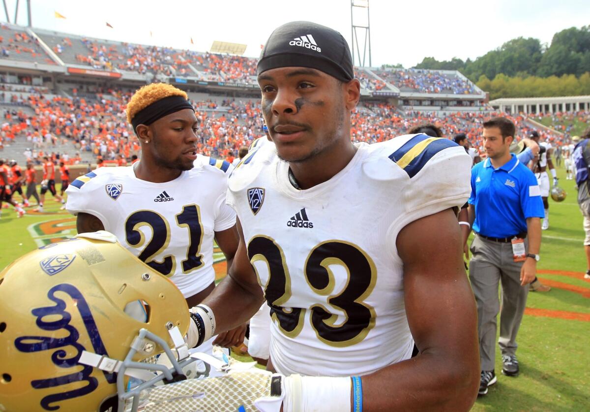 UCLA running back Nate Starks, No. 23, and defensive back Tahaan Goodman, No. 21, walk off the field after the Bruins' 28-20 win over Virginia on Saturday at Scott Stadium in Charlottesville, Va.