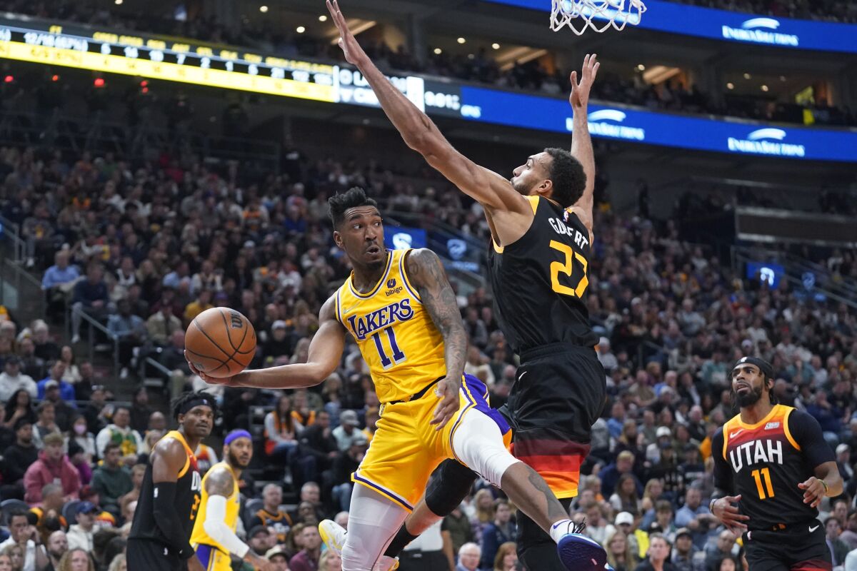 Lakers guard Malik Monk passes the ball as Utah Jazz center Rudy Gobert defends.