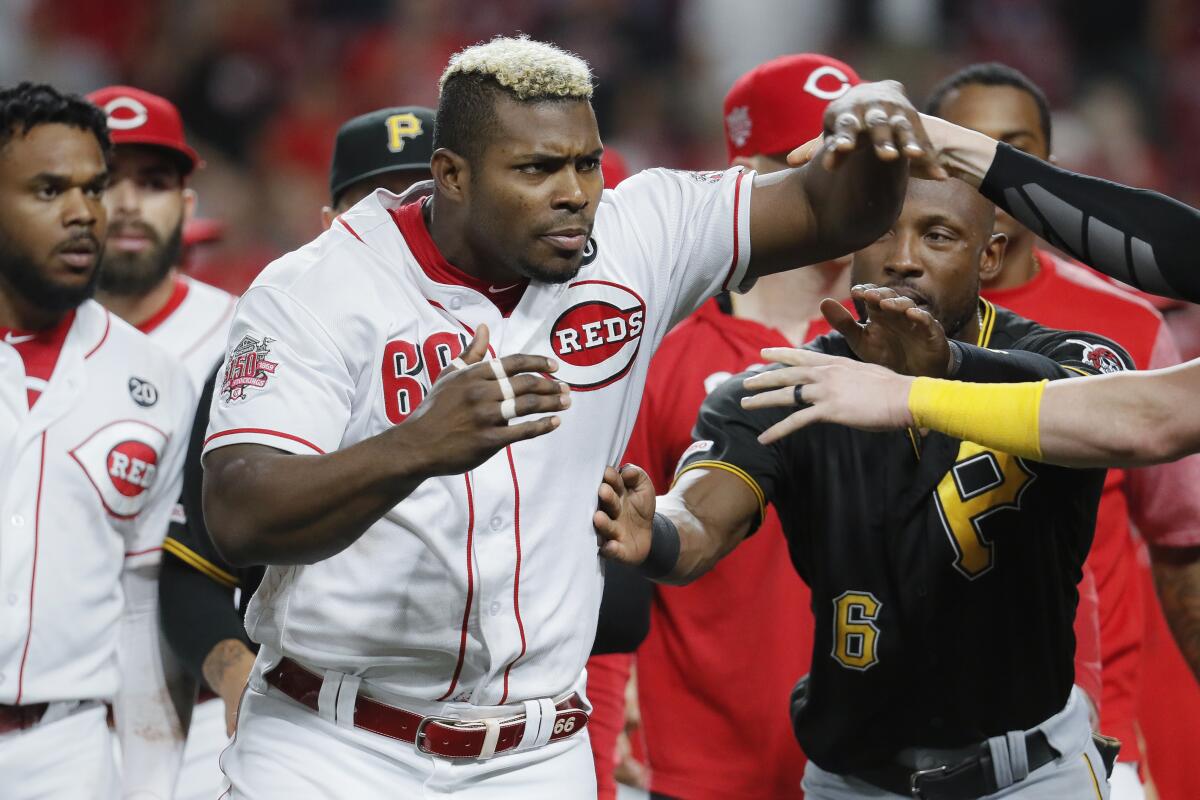 Cincinnati Reds right fielder Yasiel Puig (66) is restrained during a bench-clearing in the ninth inning of a baseball game against the Pittsburgh Pirates, Tuesday, July 30, 2019, in Cincinnati. (AP Photo/John Minchillo)