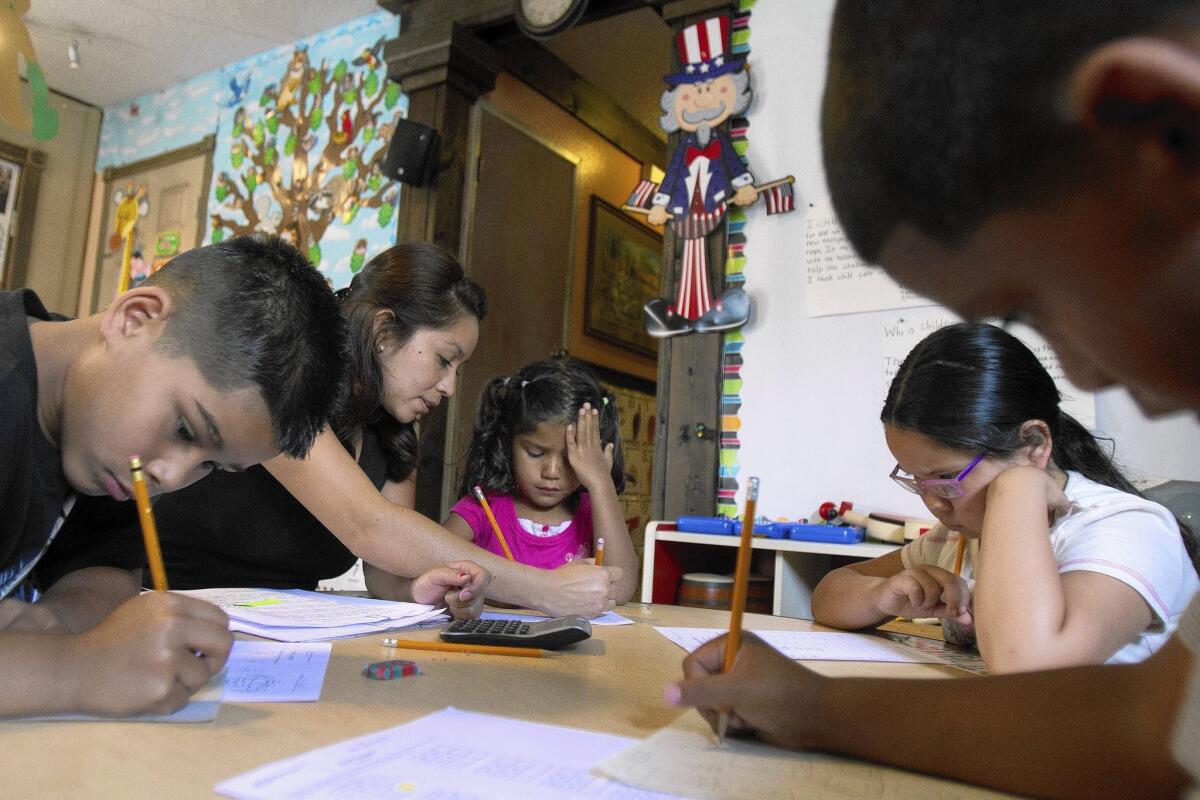Richard Fernandeezes, from left, teaching assistant Carla Delgado, Richard's sister Jasmine, Yaritza Trujillo and Richard's brother, Jacob, fill out worksheets at a private child-care center in Long Beach.