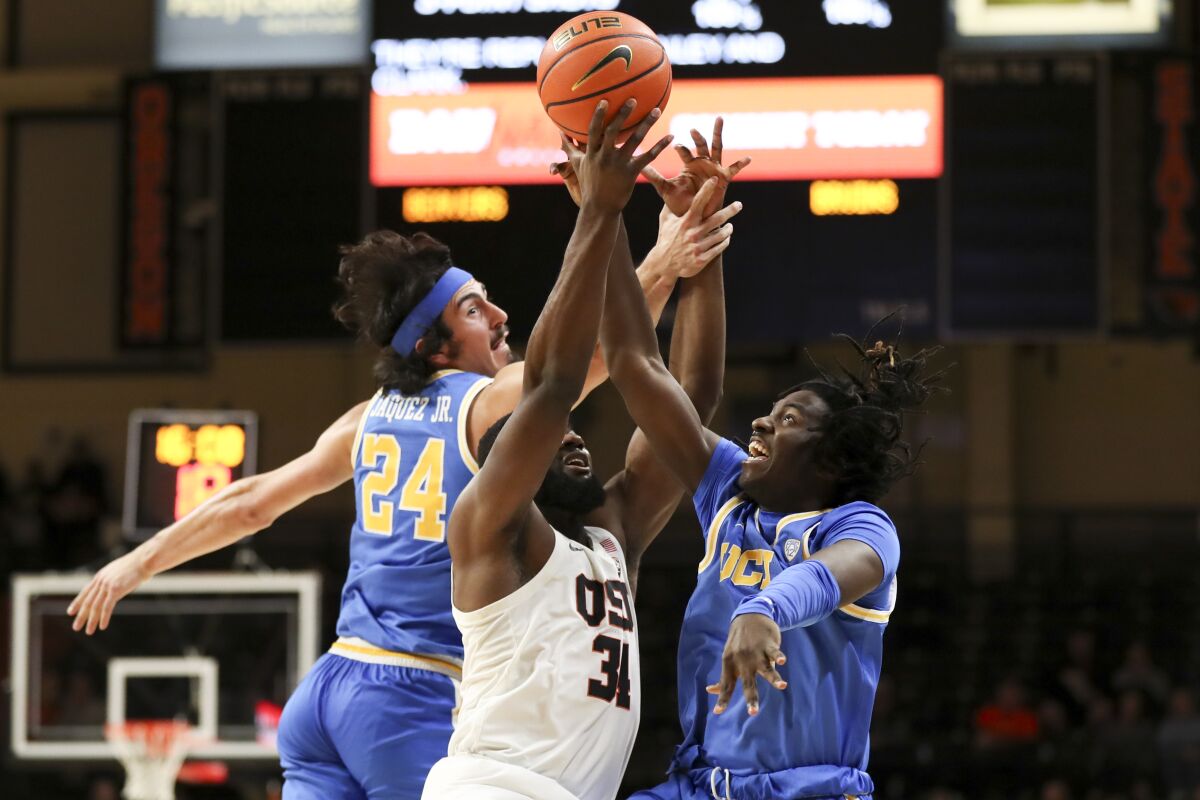 UCLA's Jaime Jaquez Jr. and Will McClendon reach for a pass meant for Oregon State forward Rodrigue Andela.
