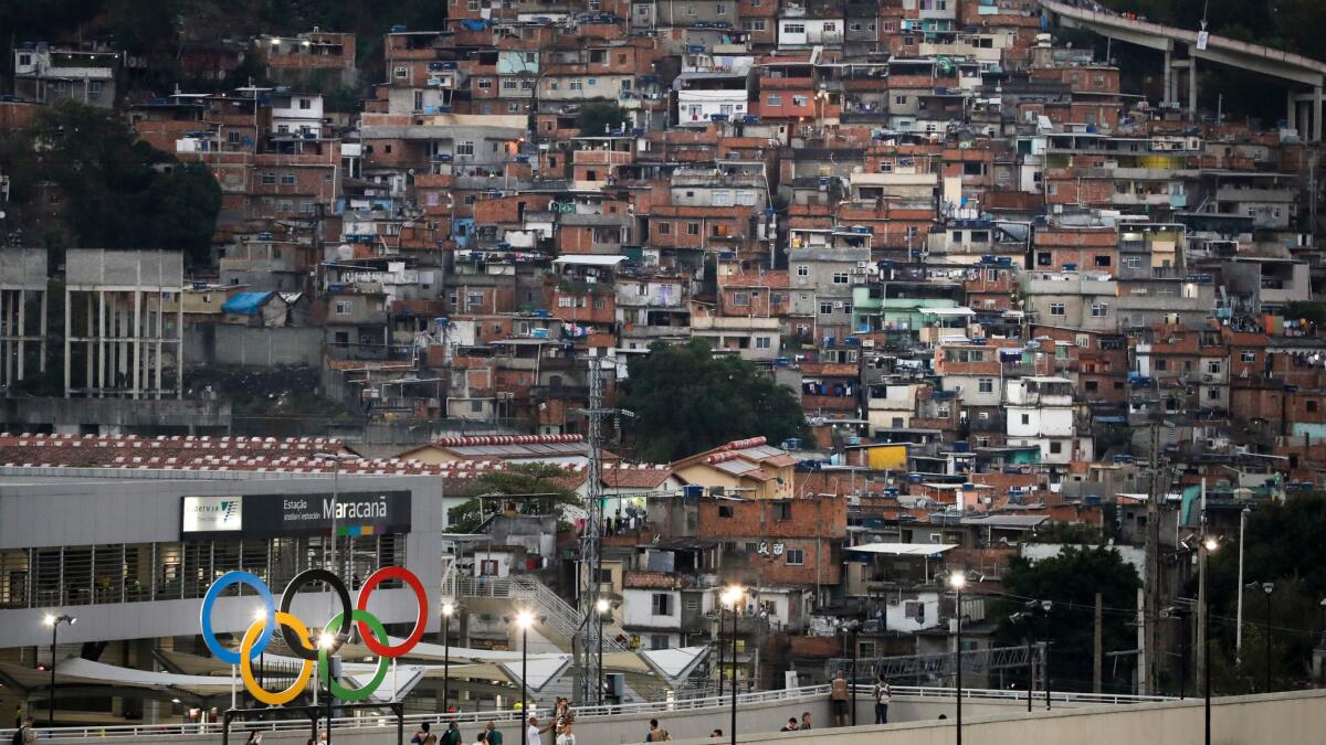 Olympic rings adorn Maracana Stadium ahead of the opening ceremony for the 2016 Summer Olympics in Rio de Janeiro, with hillside slums visible in the distance.