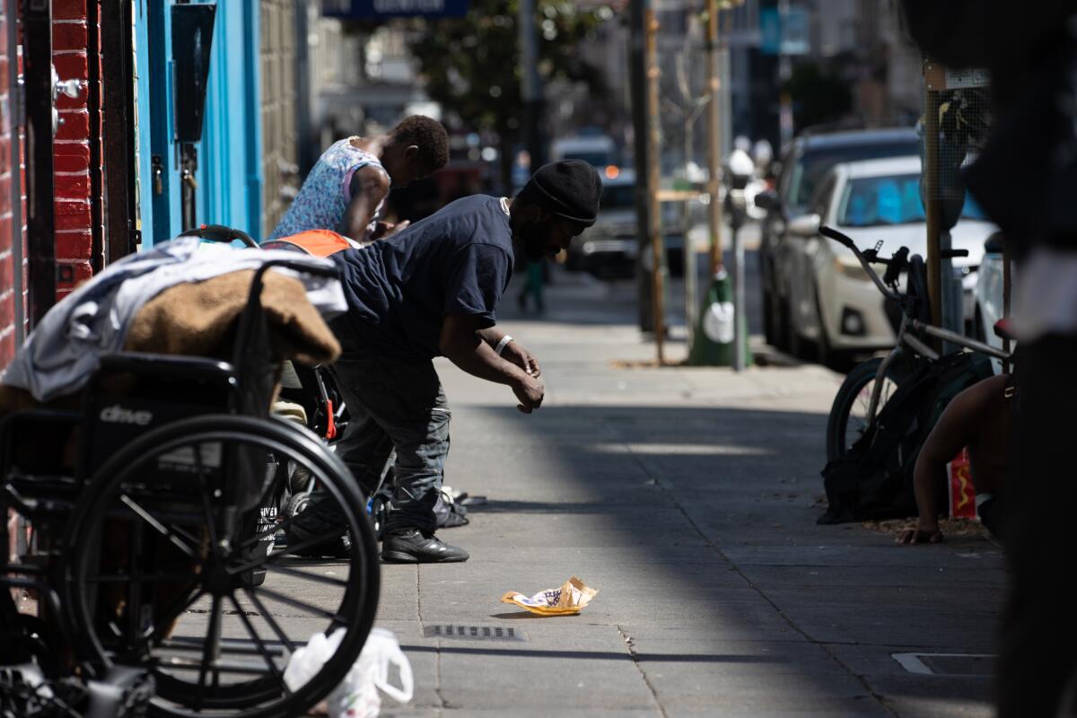People and wheelchairs on a sidewalk.