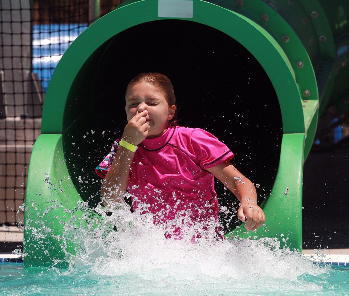 Michelle Kernacs, 9, of Burbank, takes nasal precautions as she plunges out of the tube slide at the Verdugo Aquatic Facility in Burbank on Thursday, July 24, 2014. The temperature from noon to 1:00 was near 100 degrees and pool lifeguards said attendance was higher than normal.