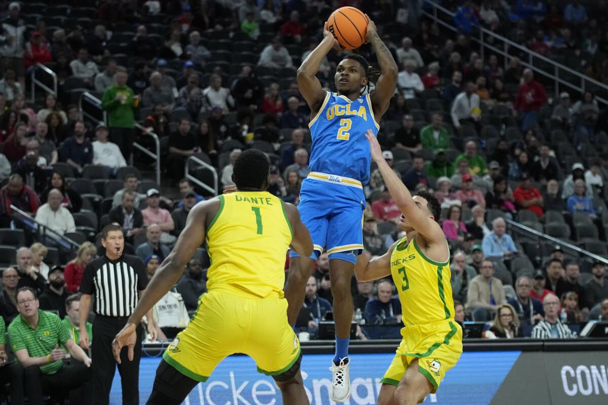 UCLA guard Dylan Andrews shoots over Oregon center N'Faly Dante and guard Jackson Shelstad.