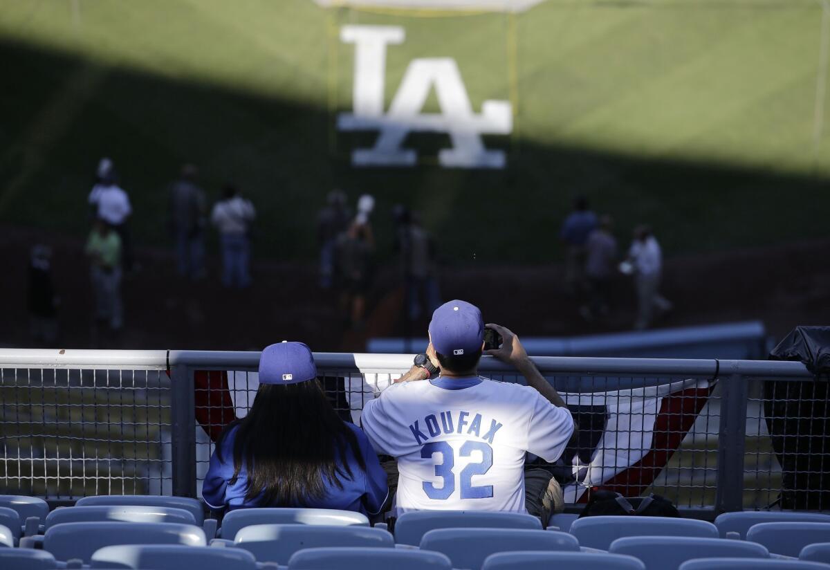 A couple Dodgers fans take in batting practice before the start of Game 4 of the NLCS on Tuesday. Knowing the slang of the game is part of being a die-hard baseball fan.