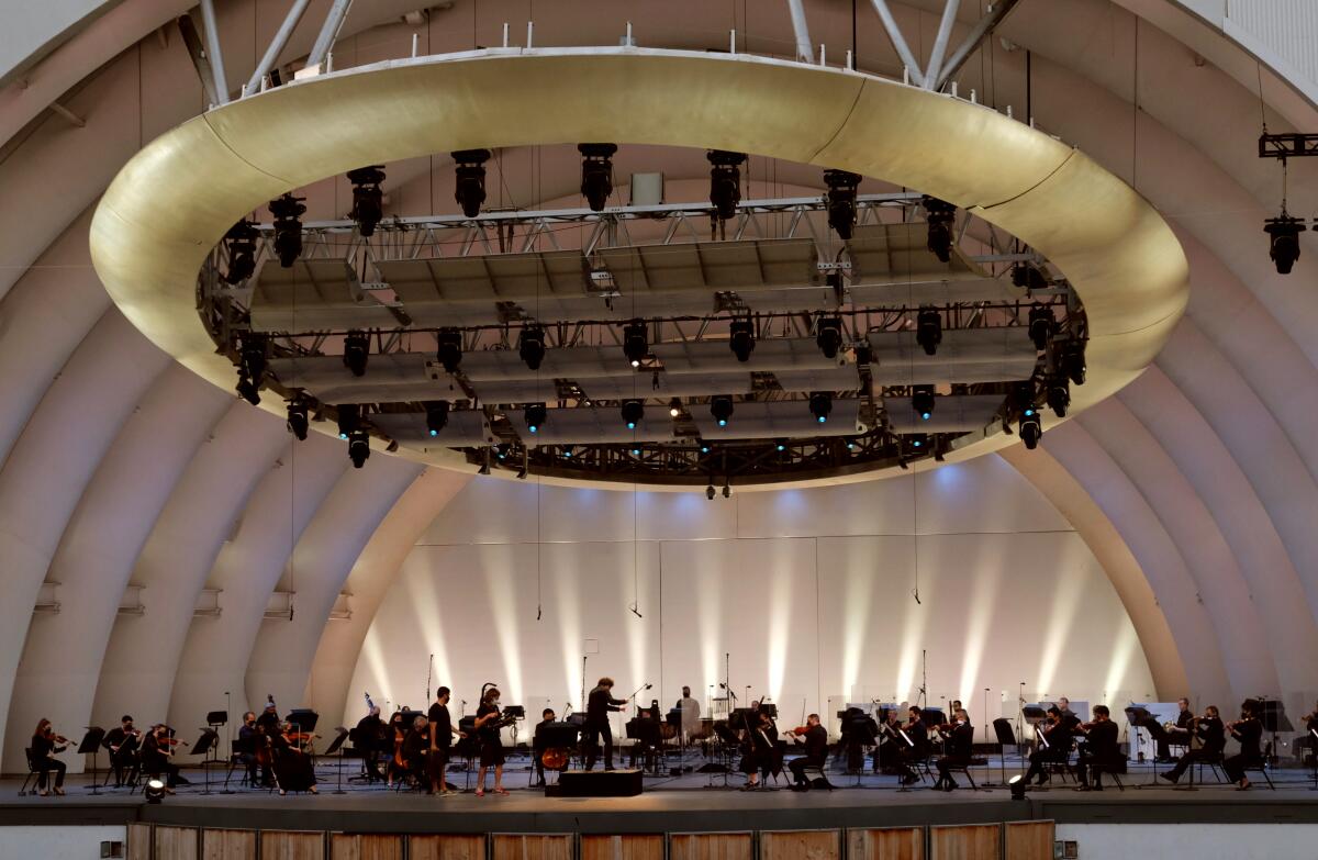 A conductor leads an orchestra on a stage.