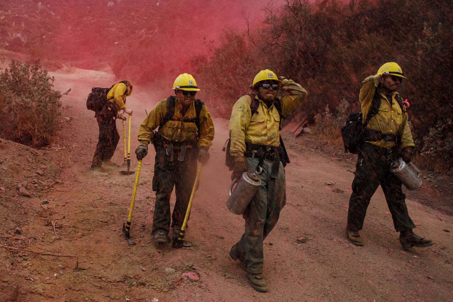 Fire crews from Ventura County brace themselves as fire retardant falls on them after being dropped from the sky while they work to stop the progression of the Holy fire in Lake Elsinore.