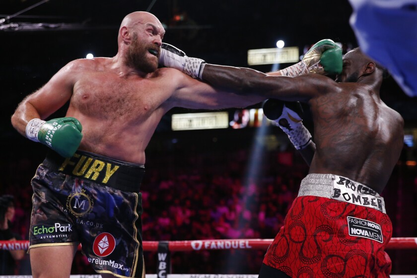 FILE - Tyson Fury, of England, hits Deontay Wilder in a heavyweight championship boxing match on Oct. 9, 2021, in Las Vegas. (Heavyweight boxing’s landscape should become a lot clearer this week when the promoters of Tyson Fury and Dillian Whyte conclude drawn-out negotiations over a world title fight that could bring Anthony Joshua and Oleksandr Usyk into the conversation. The Fury and Whyte camps have been unable to come to an agreement over the split of fight revenue for their proposed fight for the WBC and Ring Magazine belts currently held by Fury. (AP Photo/Chase Stevens, File)