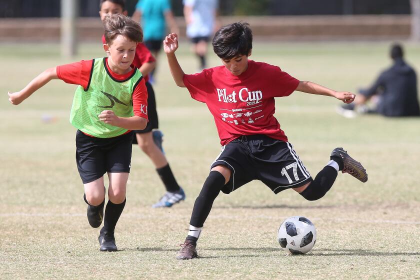 Costa Mesa Adams Elementary's Christian Sotomayor, right, makes a move on a Costa Mesa Kaiser defender in a boys' fifth- and sixth-grade Silver Division pool-play match at the Daily Pilot Cup on Friday at Jack R. Hammett Sports Complex in Costa Mesa.