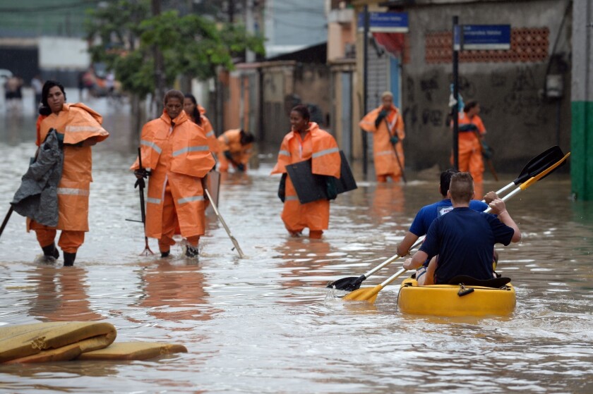 City hall workers walk in a flooded street of a suburb of Rio de Janeiro on Thursday.