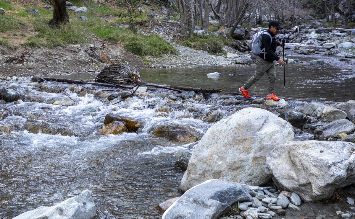 A hiker crosses a river.