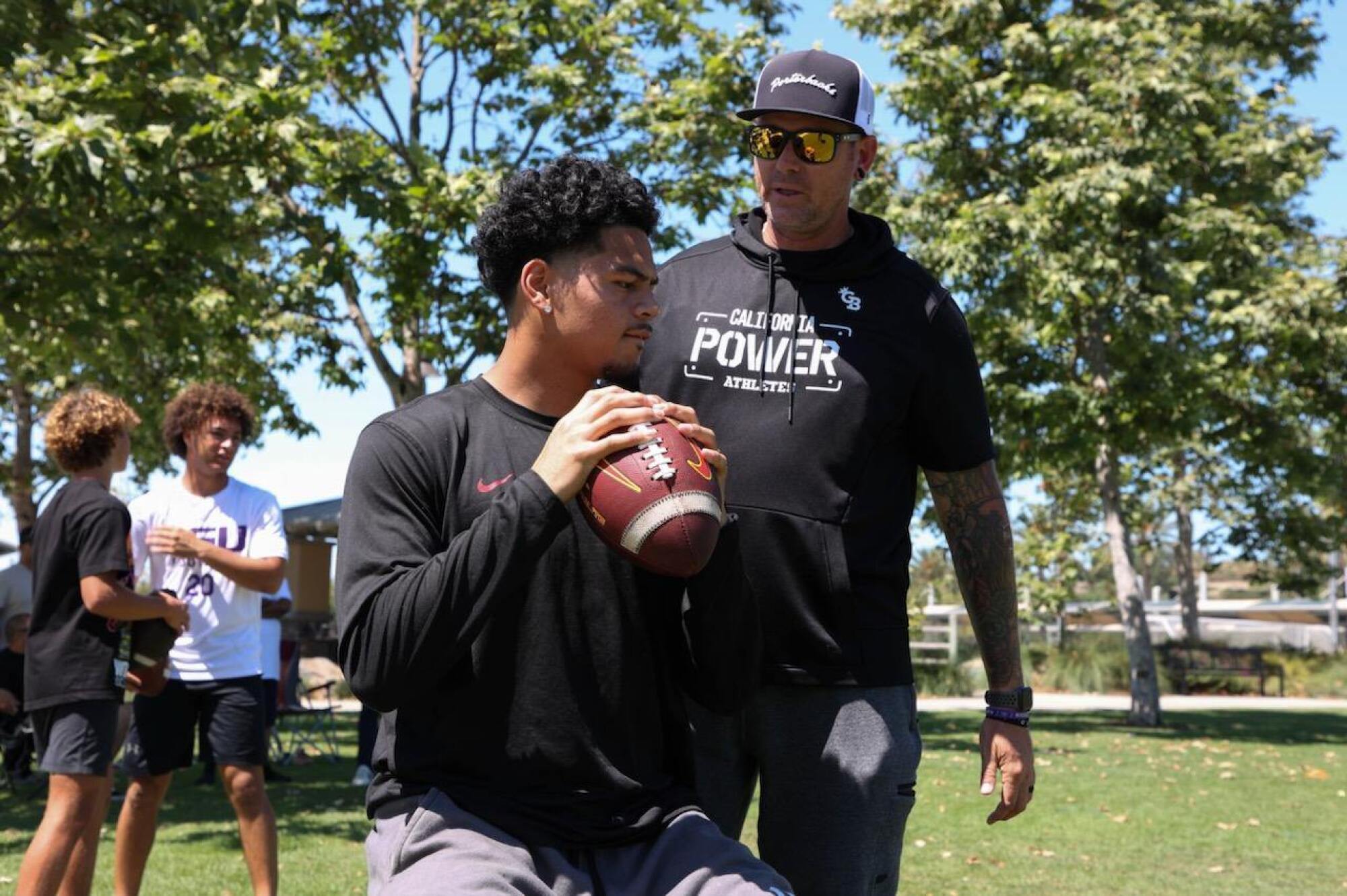 USC quarterback Jayden Maiava prepares to pass the ball while personal quarterback coach Ryan Porter watches.