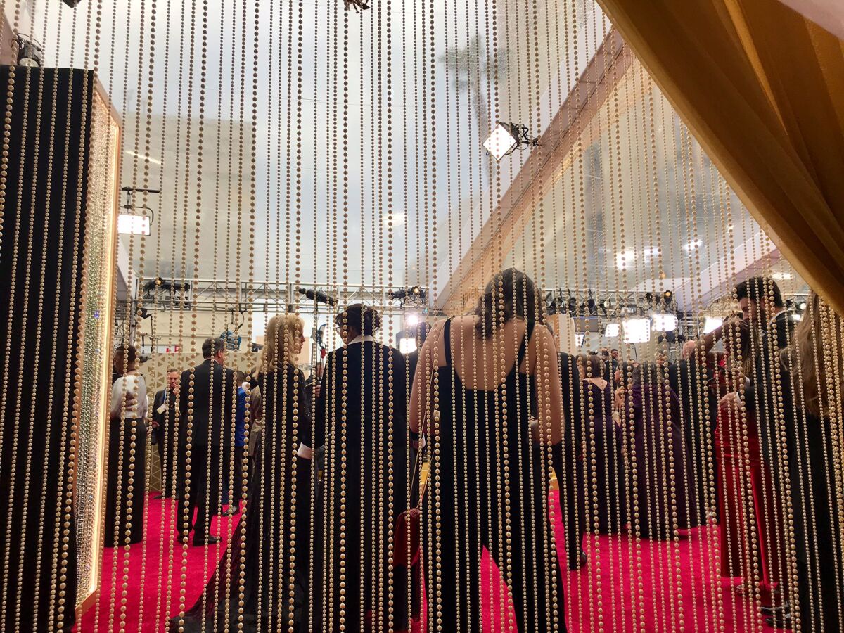 The celebrities are separated from the plebes on the carpet by a curtain of pearls (but the plebes on this side also include a few studio heads).