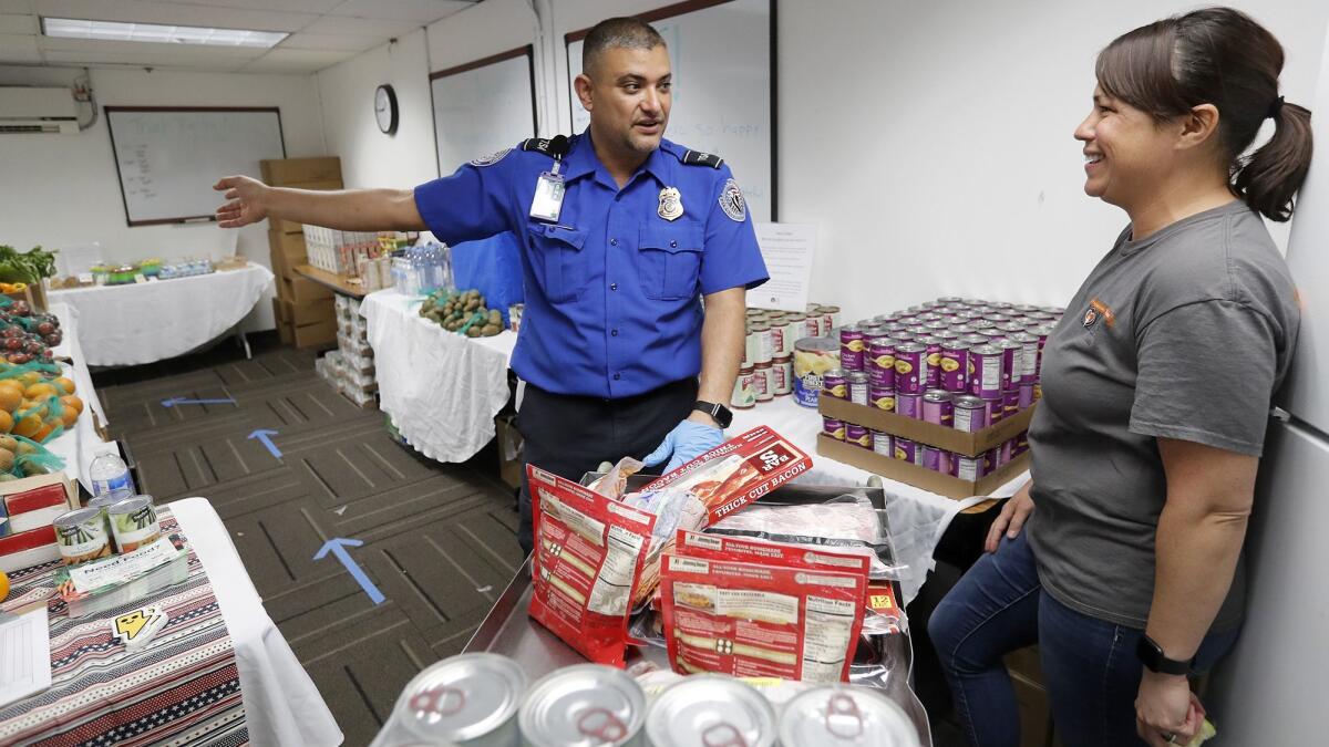 TSA employee Steve Rivera talks with Joylani Kamalu of Second Harvest Food Bank of Orange County at a temporary food pantry Second Harvest set up at John Wayne Airport to ease the effects of the government shutdown on federal workers.