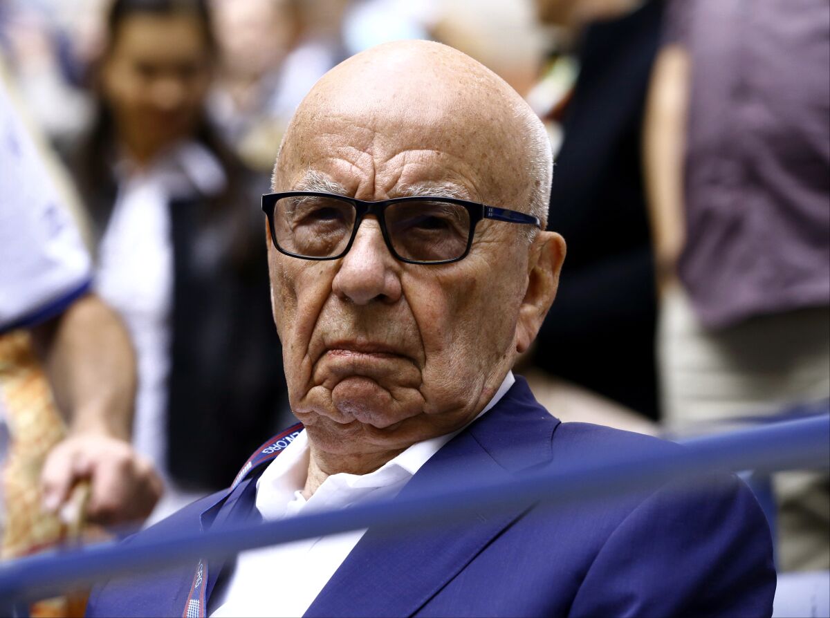 Rupert Murdoch, wearing a blue suit and dark glasses