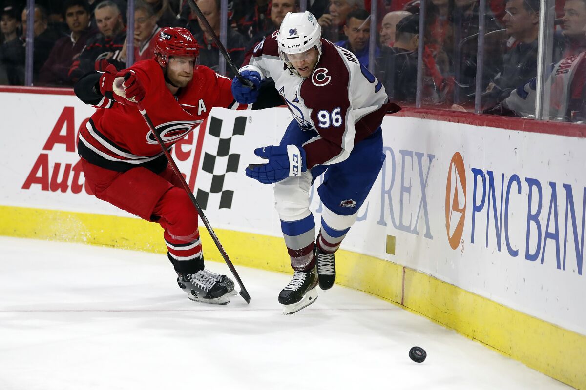 Carolina Hurricanes' Jaccob Slavin (74) and Colorado Avalanche's Mikko Rantanen (96) vie for the puck during the first period of an NHL hockey game in Raleigh, N.C., Thursday, March 10, 2022. (AP Photo/Karl B DeBlaker)